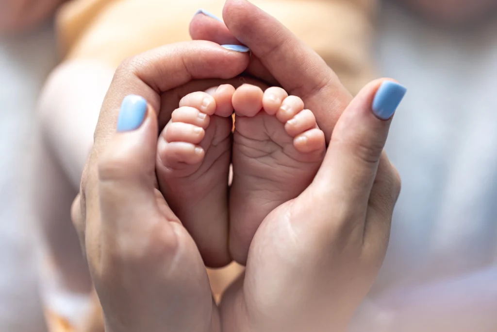 mom-holds-legs-newborn-baby-her-hands